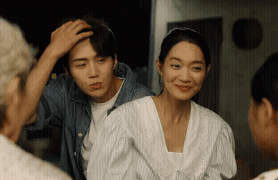 A Man And A Woman Are Standing Next To Each Other In A Room And Smiling . GIF