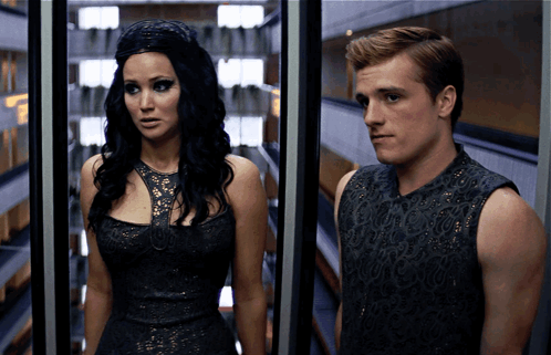 A Man And A Woman Are Standing Next To Each Other In A Room GIF