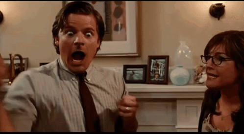 A Man And A Woman Are Standing Next To Each Other In A Room GIF