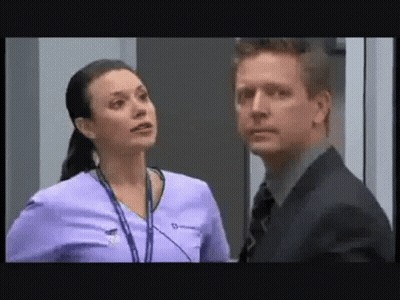 A Man And A Woman Are Standing Next To Each Other In A Room . The Man Is Wearing A Suit And Tie . GIF