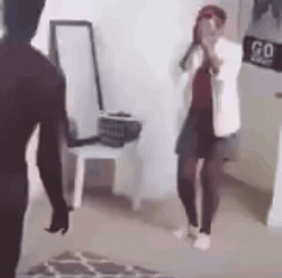 A Man And A Woman Are Standing Next To Each Other In A Room . The Woman Is Covering Her Face With Her Hands . GIF