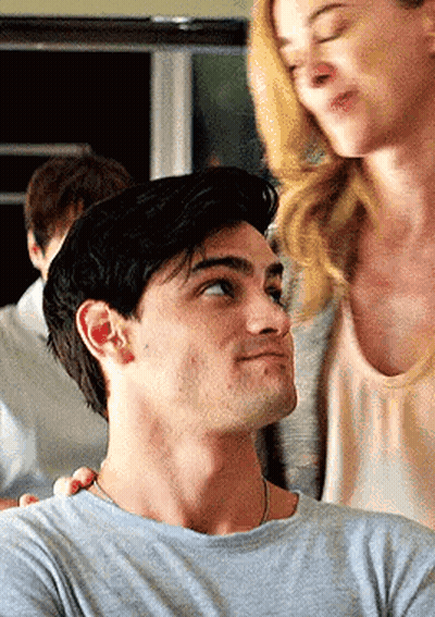 A Man And A Woman Are Standing Next To Each Other In A Room . GIF