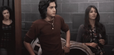 A Man And A Woman Are Standing Next To Each Other In A Room With A Brick Wall . GIF