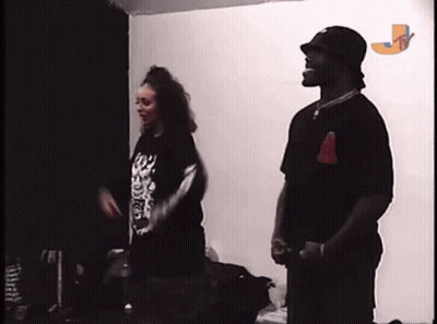 A Man And A Woman Are Standing Next To Each Other In A Room With The Letter J On The Wall GIF