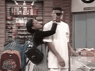 A Man And A Woman Are Standing Next To Each Other In A Store . The Woman Is Touching The Man 'S Face . GIF