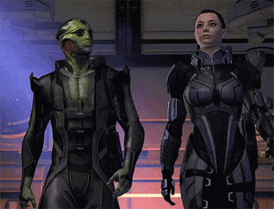 A Man And A Woman Are Standing Next To Each Other In A Video Game With The Letters N7 On Their Suits GIF