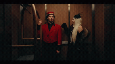 A Man And A Woman Are Standing Next To Each Other In An Elevator . GIF