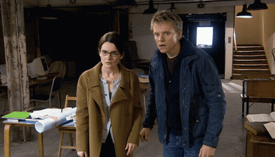 A Man And A Woman Are Standing Next To Each Other In An Office GIF