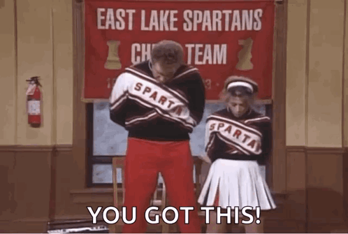 A Man And A Woman Are Standing Next To Each Other In Front Of A Banner That Says East Lake Spartans Cheer Team . GIF