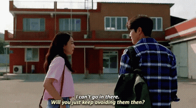 A Man And A Woman Are Standing Next To Each Other In Front Of A Building And Talking . GIF