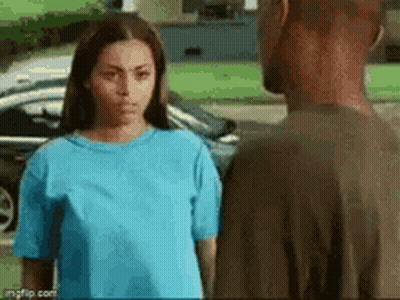 A Man And A Woman Are Standing Next To Each Other In Front Of A Car . The Woman Is Wearing A Blue Shirt . GIF