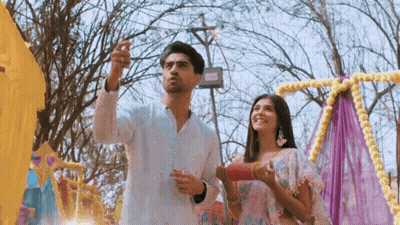 A Man And A Woman Are Standing Next To Each Other In Front Of A Colorful Display . GIF