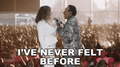 A Man And A Woman Are Standing Next To Each Other In Front Of A Crowd . GIF
