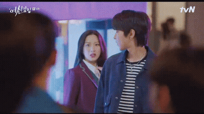 A Man And A Woman Are Standing Next To Each Other In Front Of A Crowd . GIF