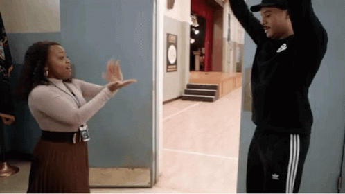 A Man And A Woman Are Standing Next To Each Other In Front Of A Door . GIF