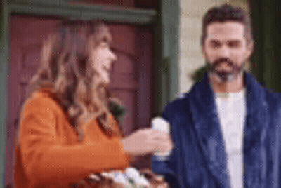 A Man And A Woman Are Standing Next To Each Other In Front Of A Door . GIF