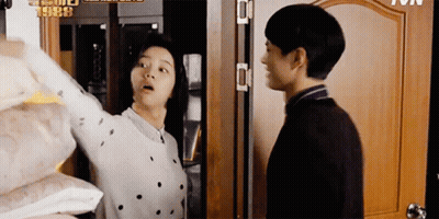 A Man And A Woman Are Standing Next To Each Other In Front Of A Door With The Year 1988 On It GIF