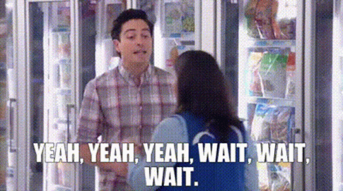 A Man And A Woman Are Standing Next To Each Other In Front Of A Refrigerator In A Store . GIF