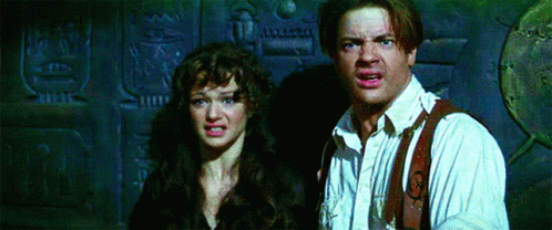 A Man And A Woman Are Standing Next To Each Other In Front Of A Wall GIF