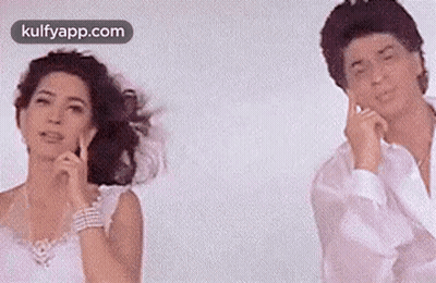 A Man And A Woman Are Standing Next To Each Other In Front Of A White Background . GIF