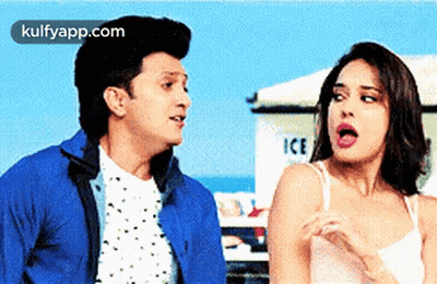 A Man And A Woman Are Standing Next To Each Other In Front Of An Ice Truck . GIF