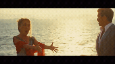 A Man And A Woman Are Standing Next To Each Other In Front Of The Ocean GIF