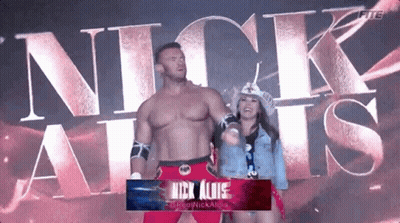 A Man And A Woman Are Standing Next To Each Other In Front Of The Word Nick Allis GIF