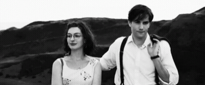A Man And A Woman Are Standing Next To Each Other On A Hill . GIF