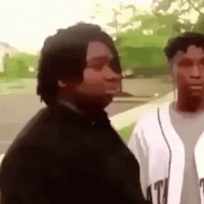 A Man And A Woman Are Standing Next To Each Other On A Sidewalk And Looking At Each Other . GIF