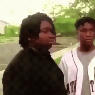 A Man And A Woman Are Standing Next To Each Other On A Sidewalk And Looking At Each Other . GIF