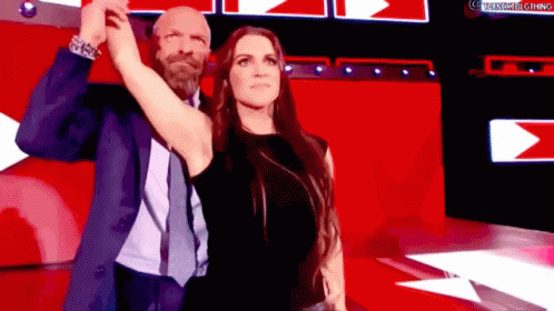 A Man And A Woman Are Standing Next To Each Other On A Stage . GIF