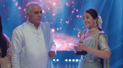 A Man And A Woman Are Standing Next To Each Other On A Stage . GIF