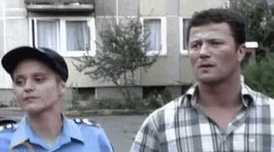 A Man And A Woman Are Standing Next To Each Other On A Street . GIF