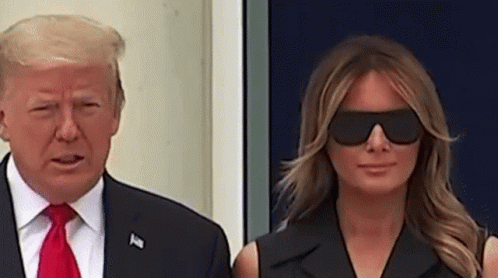 A Man And A Woman Are Standing Next To Each Other Wearing Sunglasses . GIF