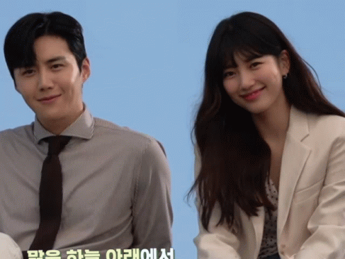A Man And A Woman Are Standing Next To Each Other With A Blue Background GIF
