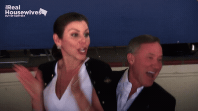 A Man And A Woman Are Standing Next To Each Other With A Real Housewives Logo Behind Them GIF