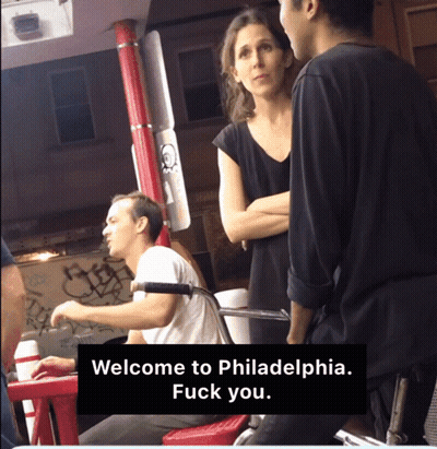 A Man And A Woman Are Standing Next To Each Other With A Sign That Says Welcome To Philadelphia Fuck You GIF
