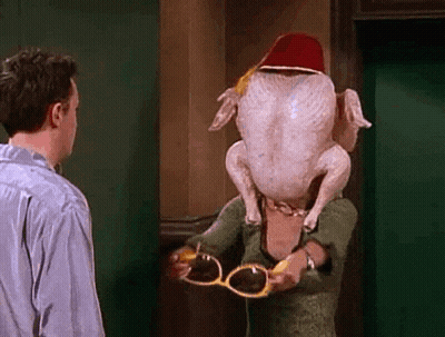 A Man And A Woman Are Standing Next To Each Other With A Turkey On Their Head . GIF