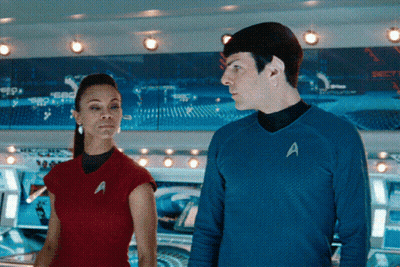A Man And A Woman Are Standing Next To Each Other With The Man Wearing A Blue Shirt With The Letter A On It GIF