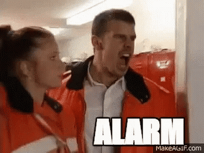 A Man And A Woman Are Standing Next To Each Other With The Word Alarm On The Bottom GIF