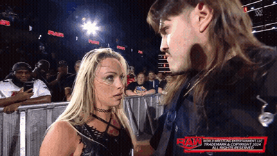 A Man And A Woman Are Standing Next To Each Other With The Word Raw On The Bottom Right GIF