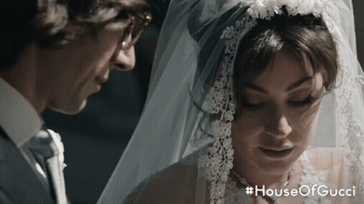 A Man And A Woman Are Standing Next To Each Other With The Words House Of Gucci On The Bottom GIF