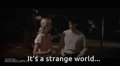 A Man And A Woman Are Standing Next To Each Other With The Words It 'S A Strange World GIF