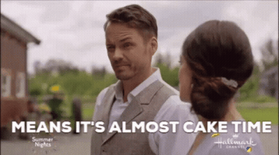 A Man And A Woman Are Standing Next To Each Other With The Words `` Means It 'S Almost Cake Time '' GIF