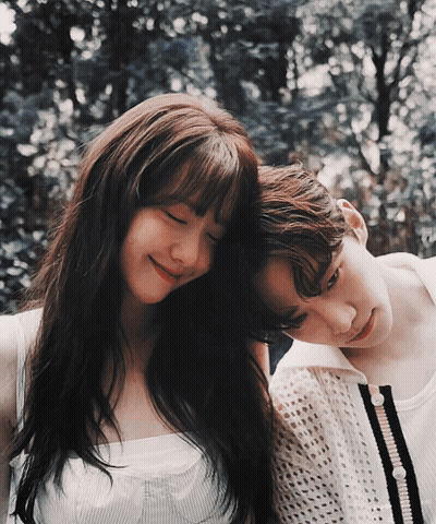 A Man And A Woman Are Standing Next To Each Other With Their Heads On Each Other 'S Shoulders GIF