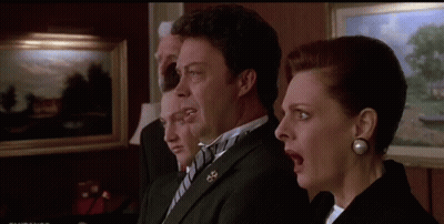 A Man And A Woman Are Standing Next To Each Other With Their Mouths Open In A Room . GIF