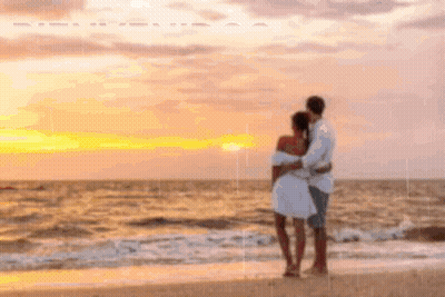 A Man And A Woman Are Standing On A Beach Looking At The Ocean At Sunset . GIF