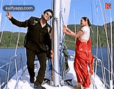 A Man And A Woman Are Standing On A Boat . GIF