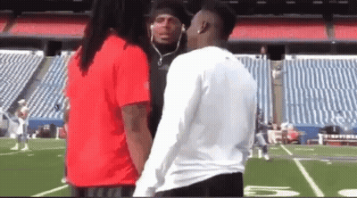 A Man And A Woman Are Standing On A Football Field . GIF