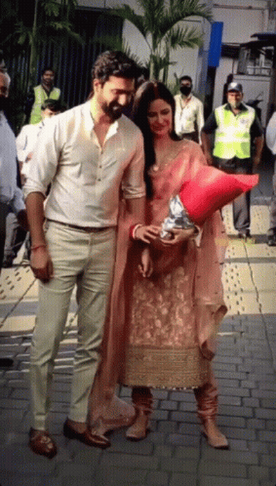 A Man And A Woman Are Standing On A Sidewalk Holding Hands GIF
